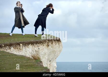 Les touristes se trouve près du bord de l'effondrement des falaises de craie à Birlng Gap, East Sussex Banque D'Images