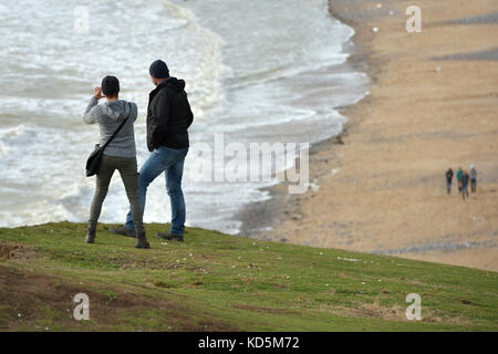 Les touristes se trouve près du bord de l'effondrement des falaises de craie à Birlng Gap, East Sussex Banque D'Images