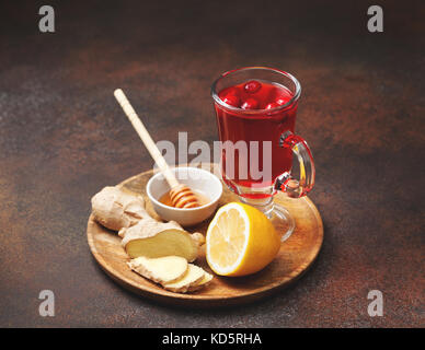 Gingembre citron cranberry boisson dans une tasse en verre, le miel, la moitié d'un citron, tranches de gingembre sur une vieille background Banque D'Images