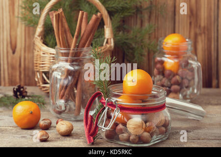 Cadeaux de Noël dans un bocal en verre : noix, noisettes, mandarines sur le vieux fond de bois Banque D'Images