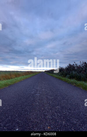 Une route disparaissant dans la distance au coucher du soleil sur les champs de l'lincolnshire fens dans en automne. fenland Banque D'Images