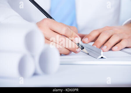 Close-up of male architect travaillant sur blueprint at desk Banque D'Images