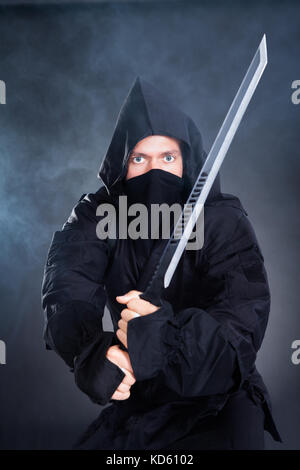 Portrait de Ninja masculin en Black Costume tenant épée Banque D'Images