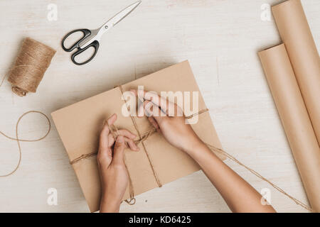 Man wrapping gift. un colis enveloppé dans du papier brun et attachées avec de la ficelle rugueuse Banque D'Images