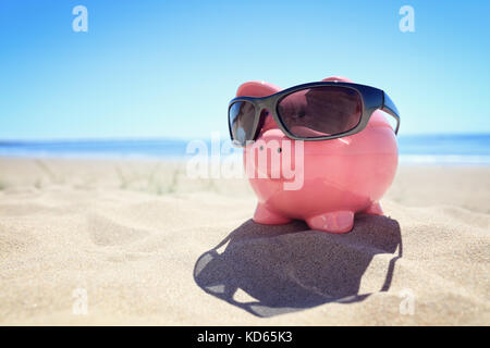 Tirelire avec lunettes de soleil sur la plage au bord de la mer Banque D'Images