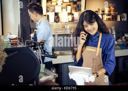 Barista asiatique parler commander par téléphone dans sa boutique. café restaurant service, propriétaire de petite entreprise, l'industrie alimentaire et des boissons concept. Banque D'Images