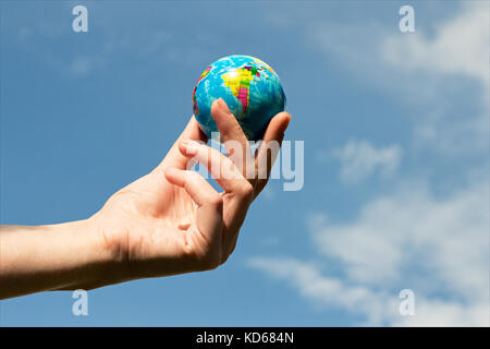 Woman's hand with globe sur fond de ciel bleu Banque D'Images