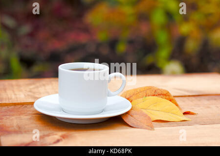 Les feuilles d'automne et la vapeur chaude tasse de café. table en bois contre les feuilles d'or. fond saison d'automne, le temps libre et pause café concept. Banque D'Images