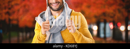 Portrait of smiling man holding wooly hat contre les feuilles sur les arbres au milieu de terrain Banque D'Images