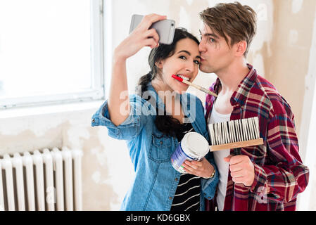 Jeune couple faisant un tout en travaillant à l'selfies rénovation de Banque D'Images