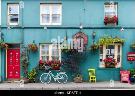 Vélo appuyé contre le mur d'un joli B&B avec fleurs, chaise, fenêtres et plantes à Skibbereen, West Cork, Irlande. Banque D'Images