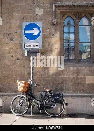 Un vélo avec un panier appuyé contre un mur en soleil à Cambridge UK Banque D'Images