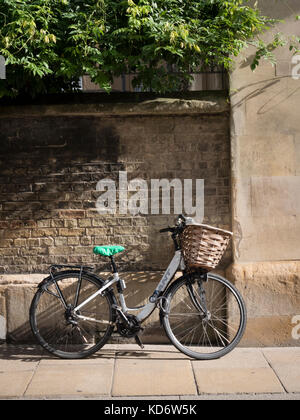 Un vélo avec un panier appuyé contre le mur du Sidney Sussex College partie de l'Université de Cambridge UK en automne Sunshine Banque D'Images