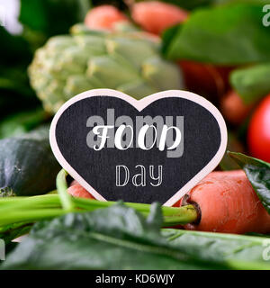 Libre d'un tableau noir en forme de cœur avec le texte de l'alimentation placé sur un tas de certains légumes crus différents, tels que les tomates, épinards, carottes ou un Banque D'Images