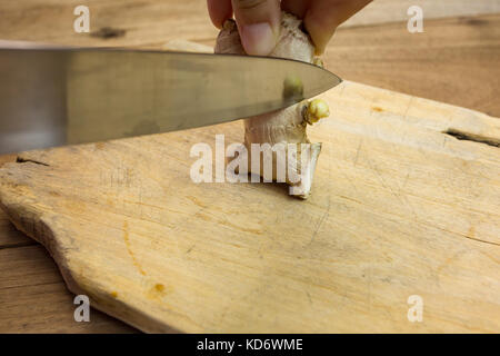 Le gingembre avec un couteau bourgeon de croissance sur une planche à découper en bois, table en bois Banque D'Images