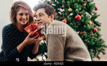 Couple heureux temps à célébrer Noël. Jeune femme assise avec son mari avec un cadeau. Banque D'Images