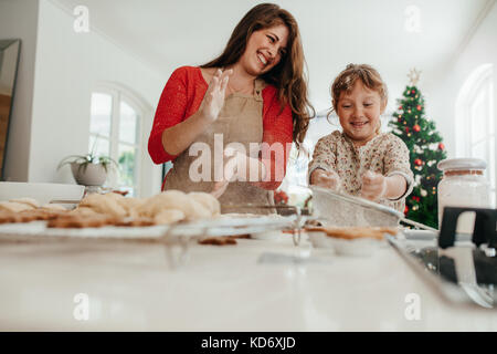 Mère et fille jouer avec cookie farine à table de cuisine tout en faisant des biscuits de Noël. Petits gâteaux et muffins sur la table de cuisine de Chri Banque D'Images