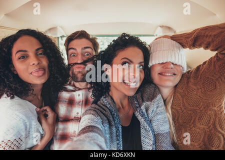 Groupe de jeunes amis fou de prendre dans les selfies van. L'homme et les femmes voyageant dans un mini van et décisions. selfies Banque D'Images