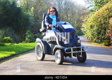 Une femme attirante utilisant un fauteuil roulant motorisé - John Gollop Banque D'Images