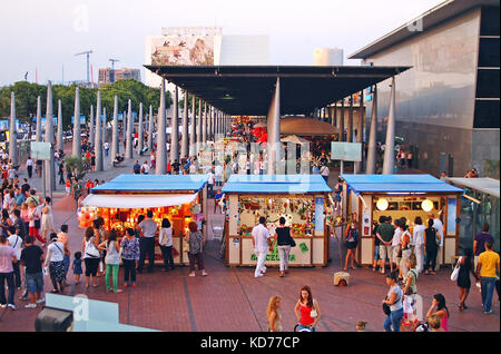 Les touristes à la recherche dans les étals de marché près de le port de Barcelone, Espagne Banque D'Images