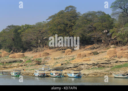 Meules de foin et des bateaux d'une ligne de rivage rocheux contrôlée le fleuve Irrawaddy en Birmanie (Myanmar). Banque D'Images