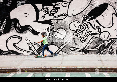 Garçon sur un scooter en face de graffitis dans Brooklyn, New York Banque D'Images