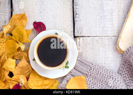 L'automne, les feuilles d'automne, la vapeur chaude tasse de café et une écharpe sur fond de table en bois. Banque D'Images