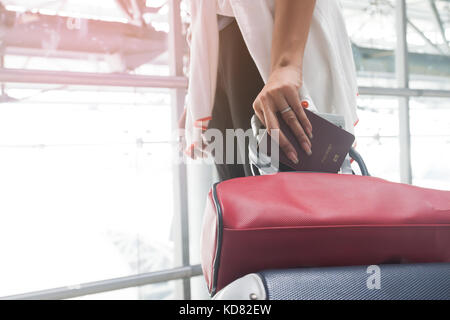 Close up of woman holding passport et faites glisser l'assurance valise à l'aéroport Banque D'Images