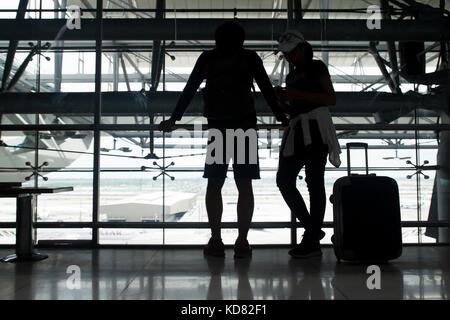 Un couple traveler Standing together en attente de l'aéroport de vol, silhouette tourné en airport Banque D'Images