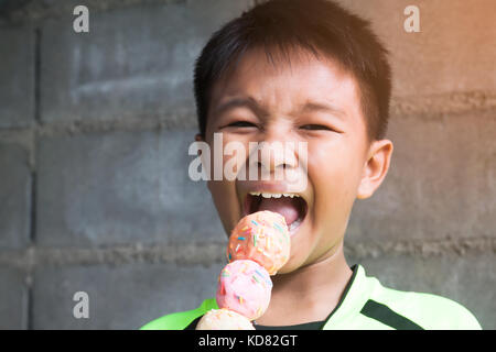 Heureux et drôle asian boy eating donut coloré Banque D'Images