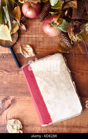 Autumn still life -vieux livre parmi les feuilles d'automne sur fond de bois.. Banque D'Images