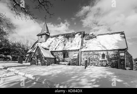 L'église de St Nicholas, Pyrford, Surrey, UK avec une couverture de neige en hiver, en noir et blanc Banque D'Images