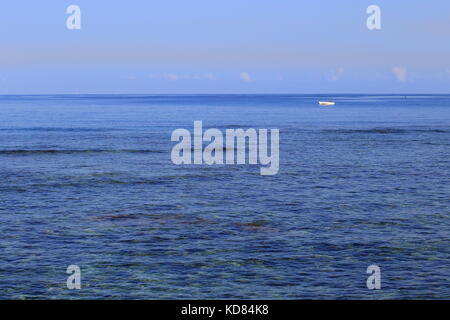 Un petit bateau blanc à la dérive d'un grand océan bleu au format paysage with copy space Banque D'Images