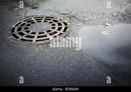 Couvercle de trou d'égout ronde en asphalte urbain Banque D'Images