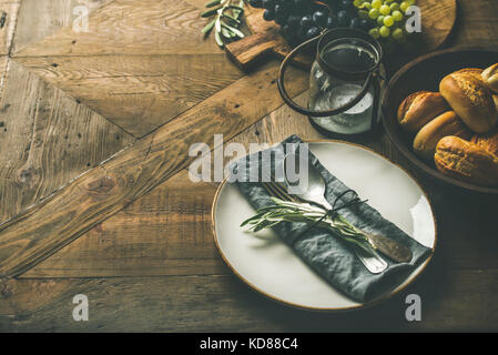 Maison de vacances automne table rustique. Plaque avec linge de maison serviette de table, fourchette et cuillère, vintage chandelier, raisins frais sur le service à bord, pain, brioches et d'olive Banque D'Images