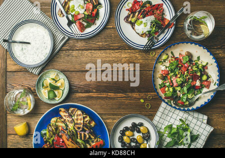 Télévision à jeter de souper santé table. Salade fraîche, légumes grillés, sauce au yogourt, les olives marinées sur fond de bois, copie de l'espace, sélectionnez Banque D'Images