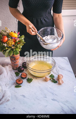 Femme tenant un bol de blancs d'œufs battus pendant la cuisson d'un gâteau Banque D'Images