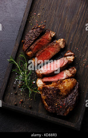 Tranches de bifteck de faux-filet grillé sur fond de bois sombre close up Banque D'Images