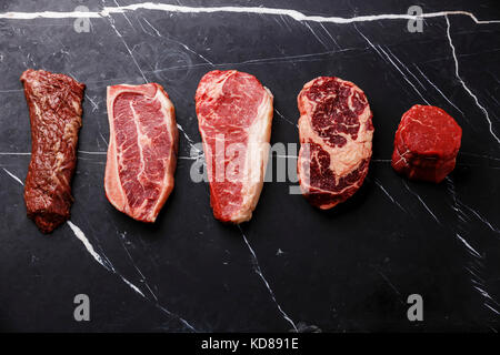 Variété de matières premier Black Angus Steak viande machette, lame sur l'os, le filet, le faux-filet, filet mignon sur fond marbre sombre copy space Banque D'Images