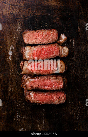 Tranches de faux-filet steak barbecue viande saignante sur fond de métal sombre Banque D'Images
