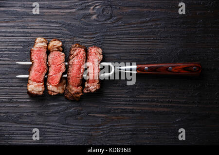 Tranches de viande barbecue steak Faux-filet sur la viande fourchette sur Burnt black background Banque D'Images