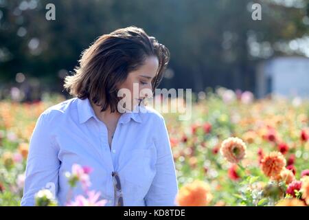 Jeune femme dans un champ de fleur en observant les fleurs Banque D'Images