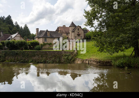 Ségur-le-Château, FRANCE - 30 juin 2017 : une vue sur la rivière Auvezere, avec une paire de canards, d'un pittoresque village médiéval du village dans le Banque D'Images