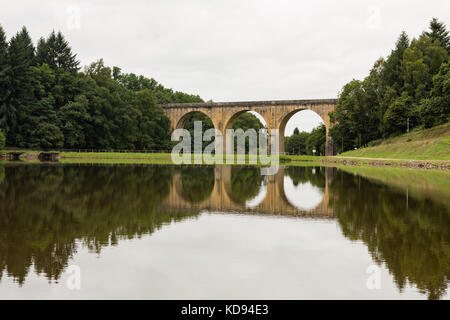 SAINT-YRIEIX-LA-PERCHE, FRANCE - 1 juillet 2017 : l'ancien pont ferroviaire voûtés reflètent dans un lac. Banque D'Images