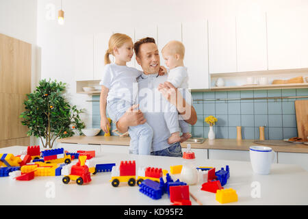 Nice bel homme debout dans la cuisine avec ses filles Banque D'Images