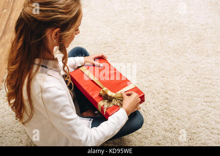 High angle view of teenage girl opening christmas present at home Banque D'Images