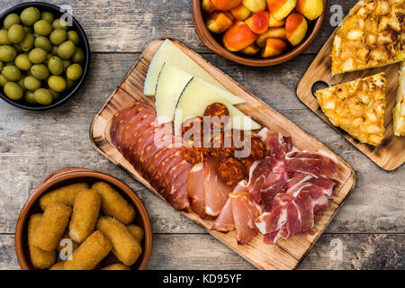 Tapas espagnoles traditionnelles. Croquettes, olives, jambon, omelette et patatas bravas sur table en bois Banque D'Images