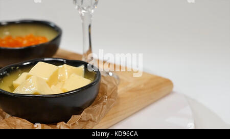 Snack, sandwichs au beurre, caviar rouge, baguette croustillante et vin blanc sur fond blanc. Caviar rouge. Citron. Verts. Pain et beurre. Banque D'Images