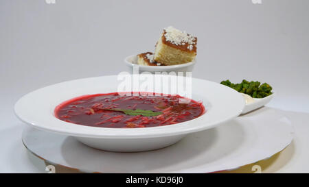 Borsch rouge avec de la viande dans l'assiette. Un délicieux borscht rouge avec de la crème sure et des herbes sur une assiette blanche. Soupe de betterave ukrainienne traditionnelle - borsch rouge et boulettes à l'ail Banque D'Images