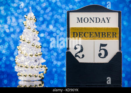 Calendrier en bois et l'arbre de Noël la réflexion sur une table en verre sur fond bleu Banque D'Images